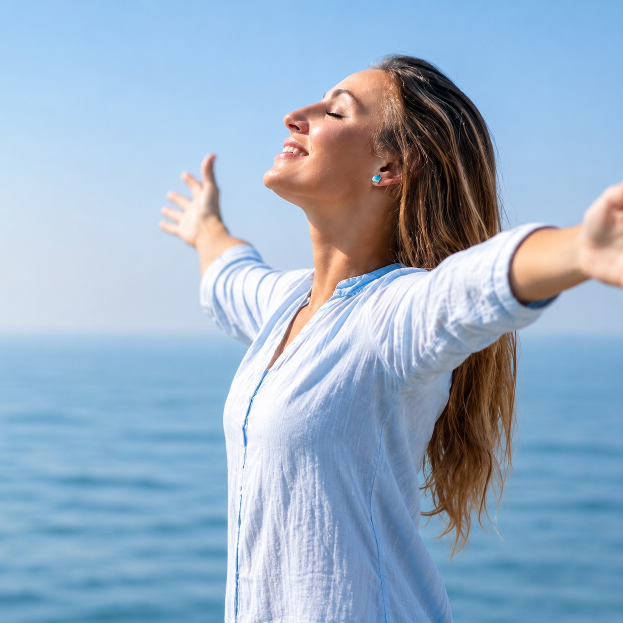 Frau am Meer mit geöffneten Armen – Symbol für Freiheit, Leichtigkeit und ein rauchfreies Leben durch Hypnose.